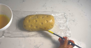 lay the cute design of puff pastry on top of turkey and brush with egg wash